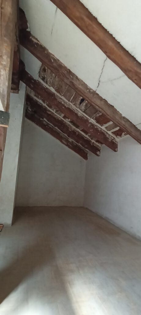 Buhardilla vacía con techo de vigas de madera.