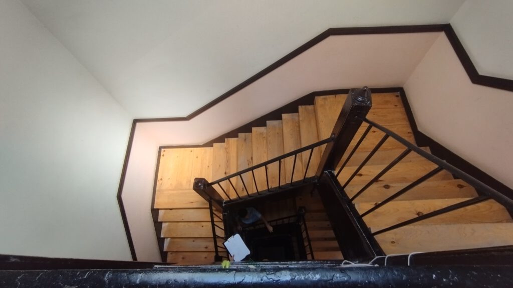 Escalera de madera en zigzag con barandilla.
