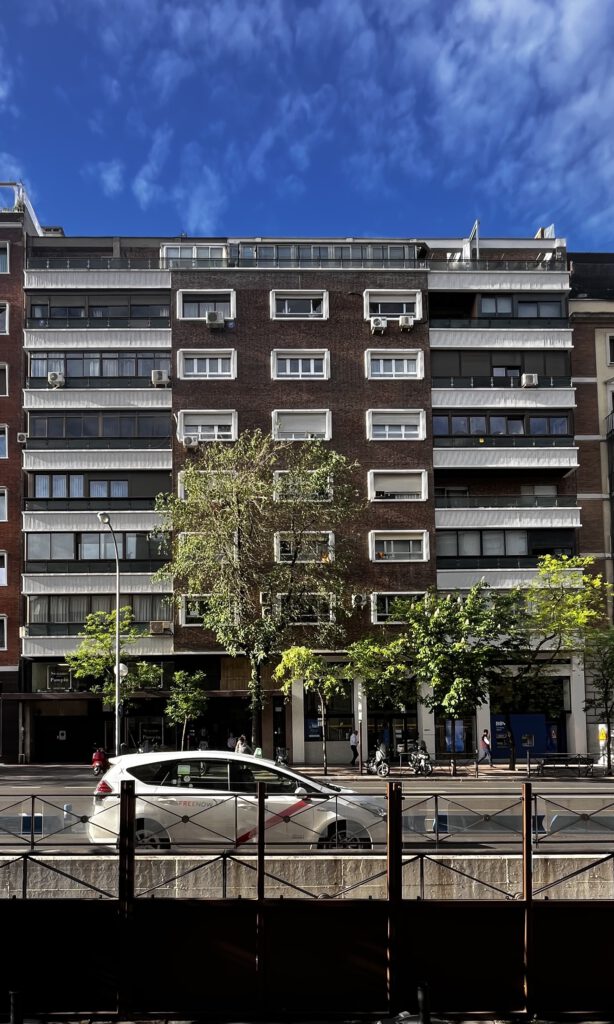 Edificio residencial en calle soleada con cielo azul.