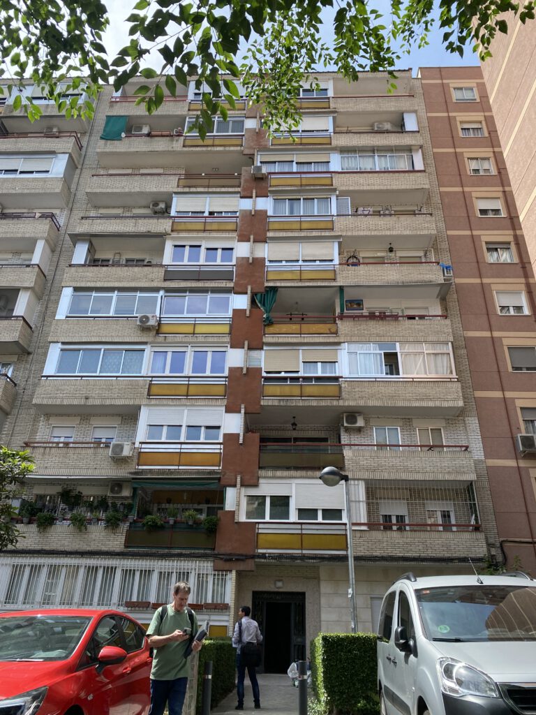 Edificio de apartamentos en la ciudad con coches delante.