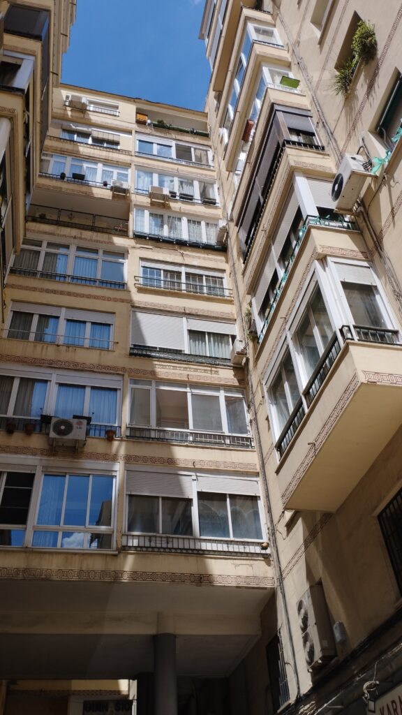 Edificio de apartamentos en un patio interior, luz solar.