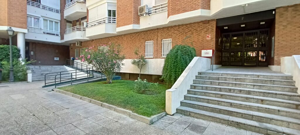 Entrada de edificio residencial con rampa y escaleras.
