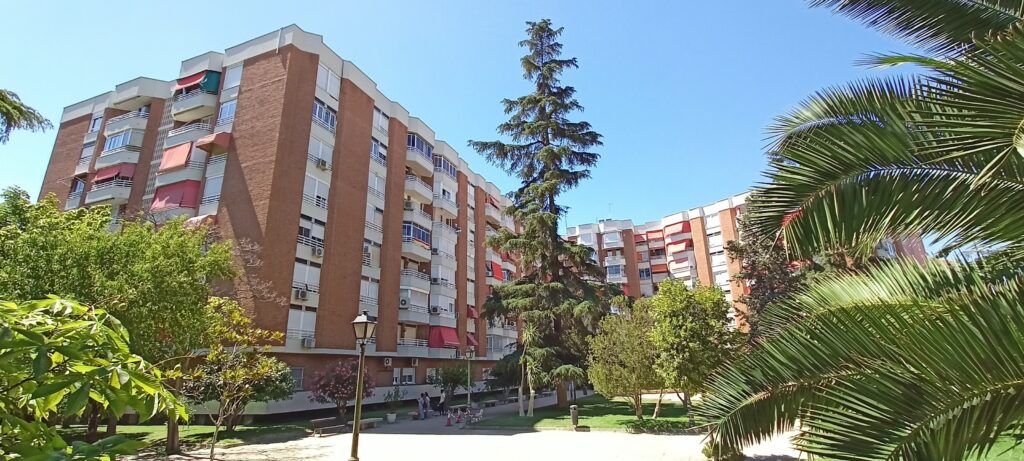 Edificio de apartamentos rodeado de árboles, cielo despejado.