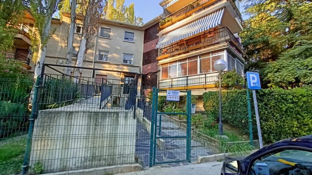 Entrada de edificio residencial con rampa y señal de aparcamiento.